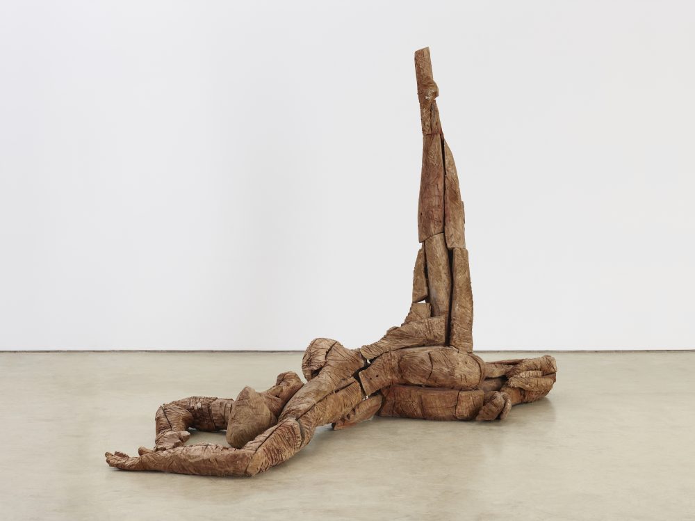 An abstract sculpture of a woman laying on the floor, with one leg raised above her.