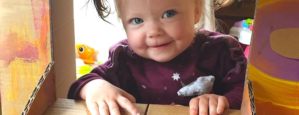 toddler playing in a homemade ice cream shop made from a cardboard box