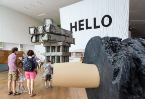 Family of 4 standing next to large scale sculptures in Firstsite's welcome area