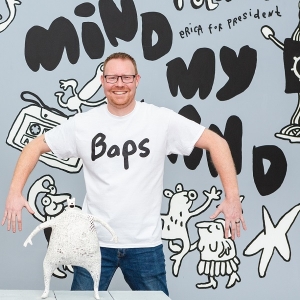 A man wearing a white t-shirt with a word Baps across the chest area.