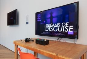 A flat screen TV showing a game called 'dreams of disguise', with controls for the game on a table.