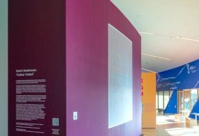 A gallery space showing a wall that has vinyl lettering reading 'Kevin Howbrook: Colour Coded'