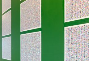 Large square printed artworks on a green wall showing a pixelated pattern.