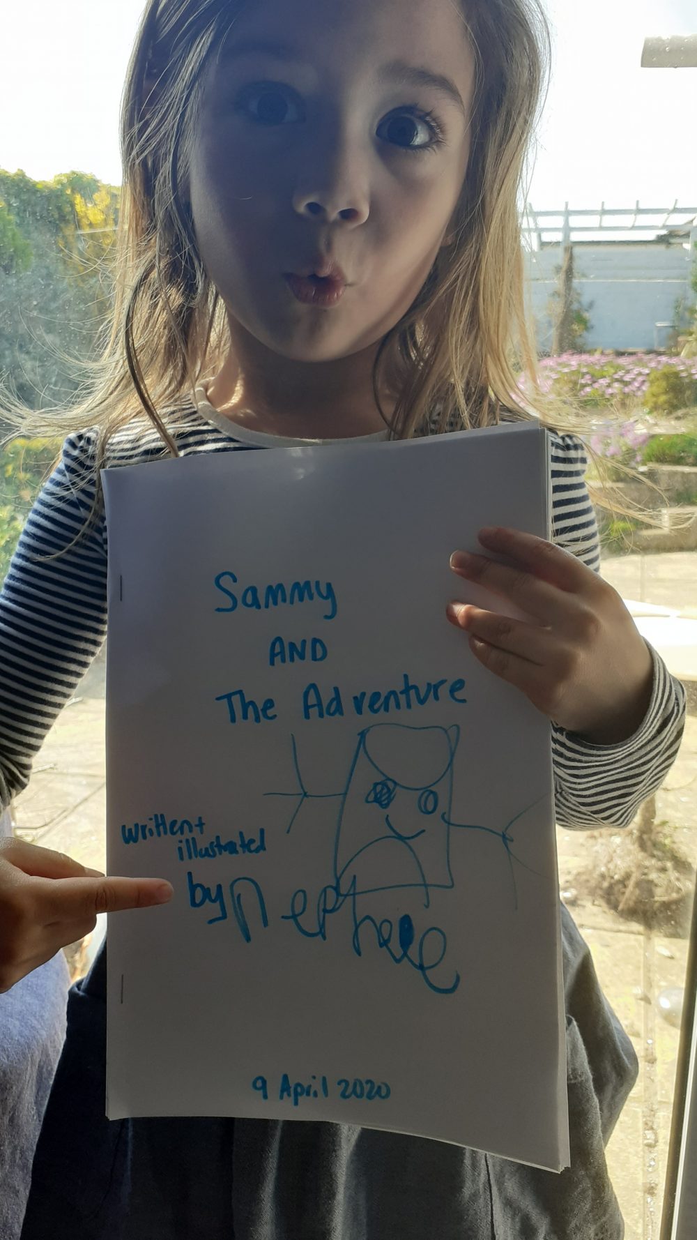 Child holding their hand written story about toilet roll.