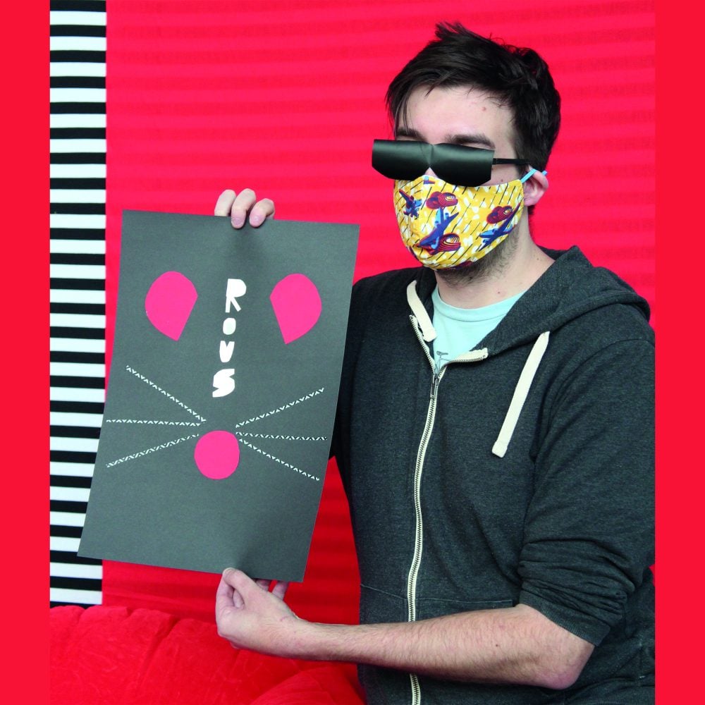 A man holding up a drawing of a mouse face in front of a red background.