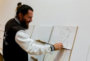 An adult draws a figure on the Heads Body Legs activity in the Landscapes and Beasts exhibition