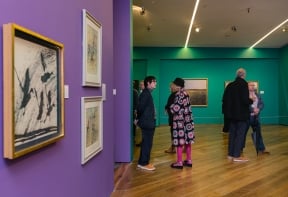 People stand in groups in the Denis Wirth Miller, Landscapes and Beasts Exhibition at Firstsite 2022.