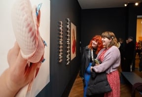 Two people looking at an artwork at the Big Women exhibition opening event.