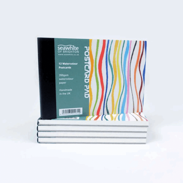 A stack of postcard pads showing the front cover including colourful stripes and a panel with information about the product.