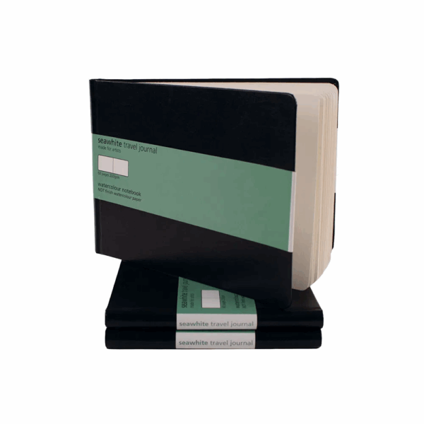 A stack of travel journals showing the front cover. Cover is black, there is a green label giving some information on the product.