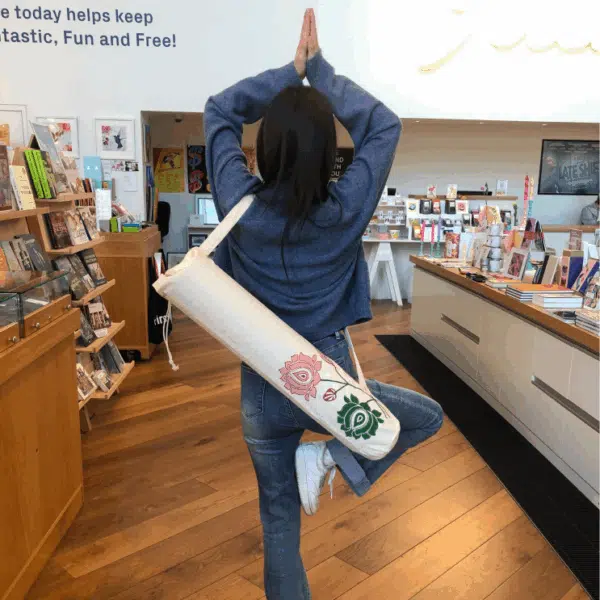 A young female in a yoga pose in a gallery shop with a yoga bag on her back